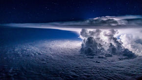 A strong cumulonimbus cloud pushes upward and flashes with lightning.